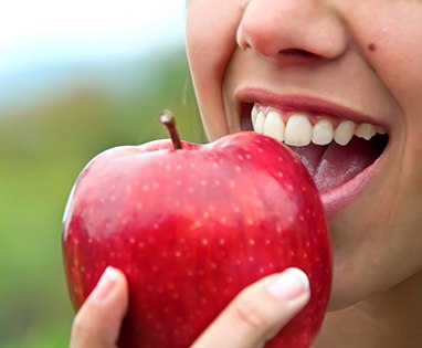 Closeup of patient with dental implants in Lincoln eating an apple