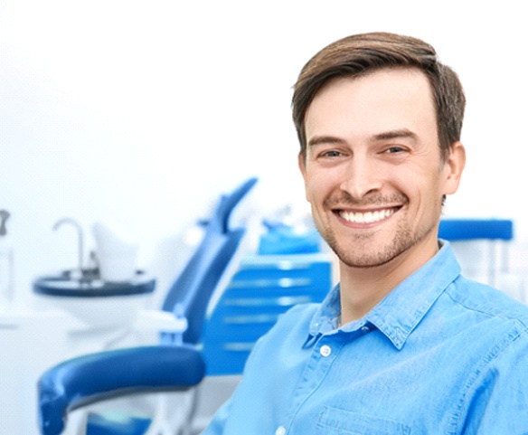 Man in blue collared shirt smiling in dental chair
