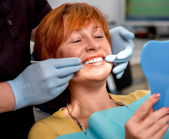 Woman in dental chair looking at smile in mirror