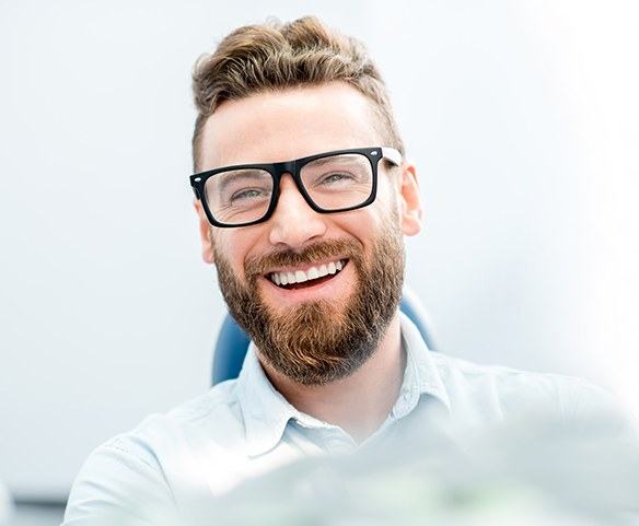 Man in dental chair smiling after periodontal treatment