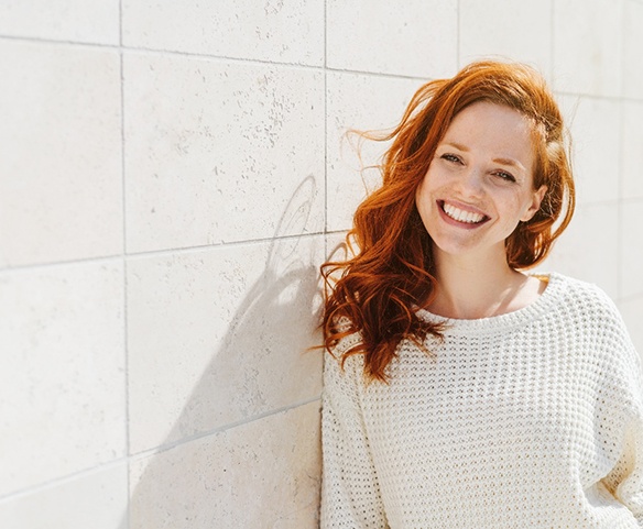 Woman smiling by a wall