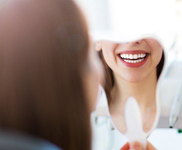 Woman looking at smile after cosmetic periodontal surgery