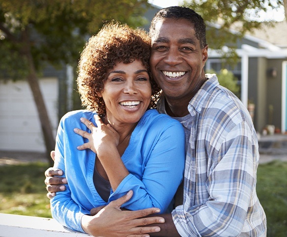 Man and woman showing off smiles after period plastic surgery