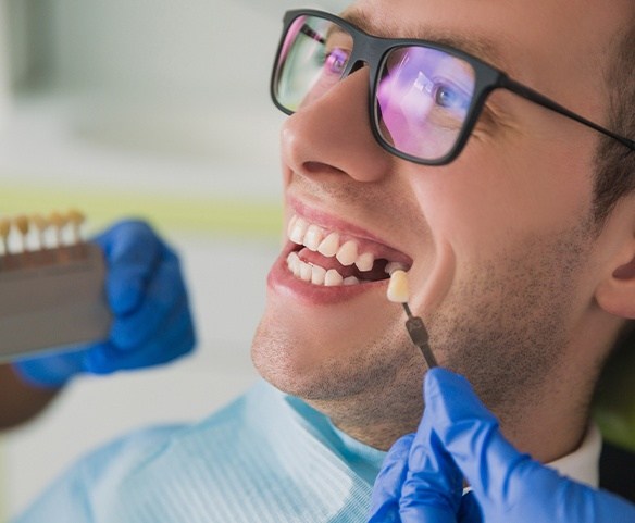 Man with missing tooth having smile compared with tooth shade chart