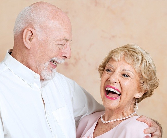 Older couple with hybridge dental implant dentures smiling