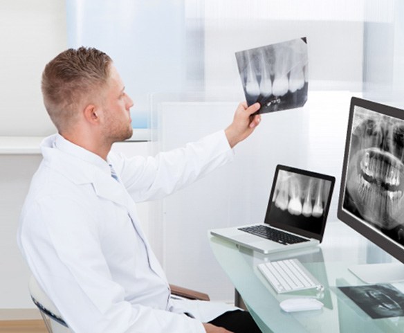 implant dentist in Lincoln, NE looking at a patient’s X-rays  