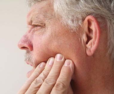 Man rubbing jaw during recovery after dental implants in Lincoln, NE