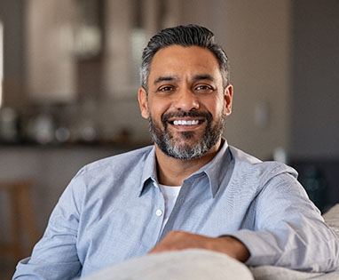 Man with dental implants in Lincoln, NE smiling on couch