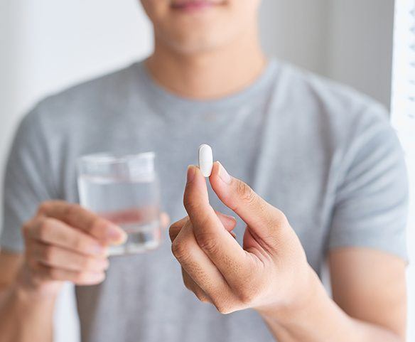 Periodontal patient holding up an antibiotic pill