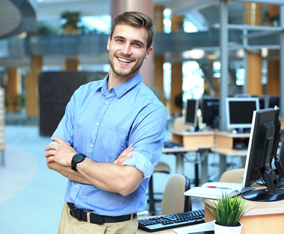 Man standing next to his workstation with arms folded