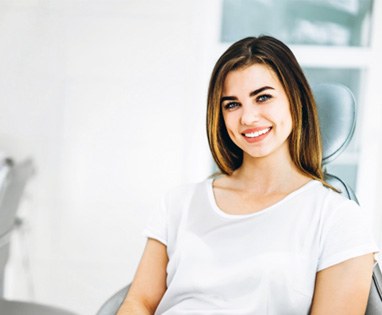 Woman in white shirt smiling in dental chair