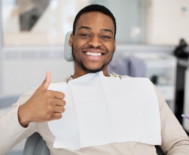Male dental patient giving a thumbs up 