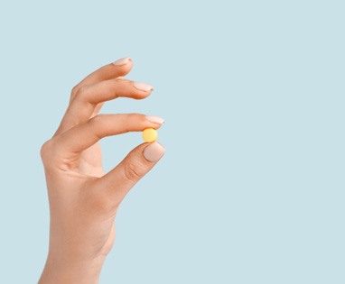 Close-up of hand holding a single pill