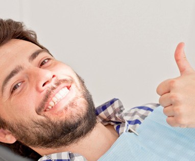 Bearded male dental patient smiling and giving thumbs up