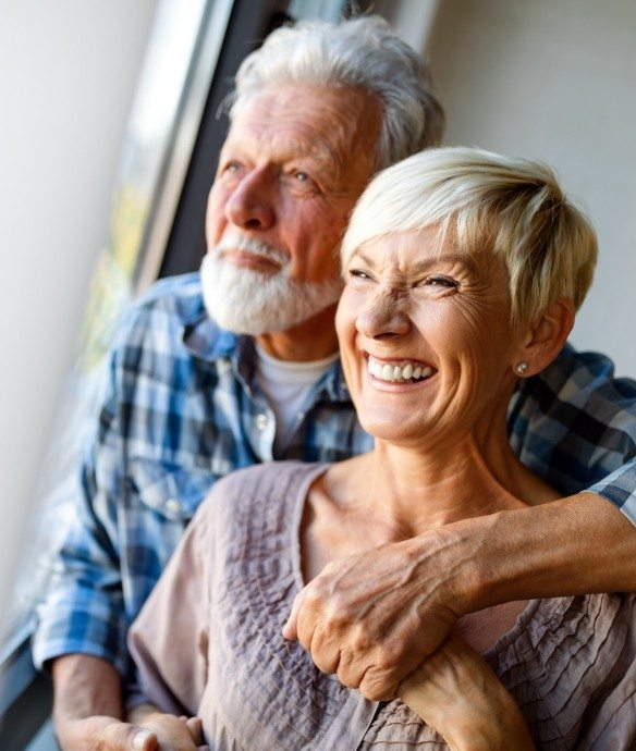 Older couple sharing healthy smiles after periodontal services in Lincoln