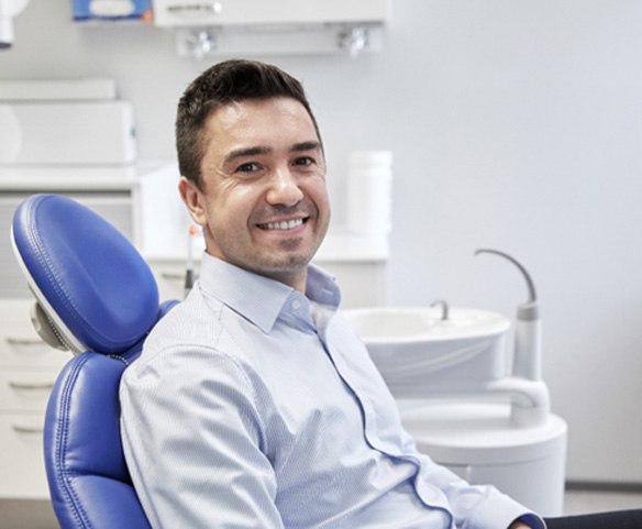 Man smiling in dental chair after receiving dental implants in Lincoln, NE