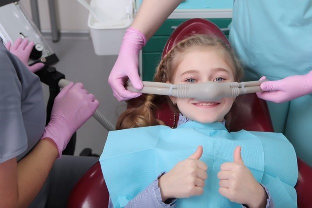 child giving thumbs up while receiving nitrous oxide sedation